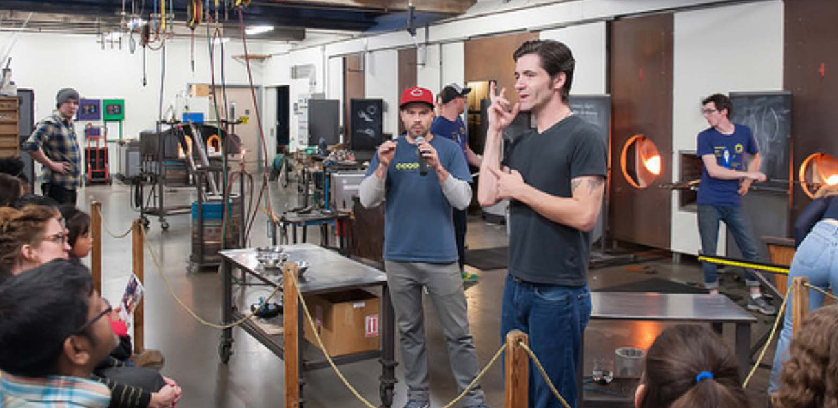 Photo of two men providing a glass blowing demonstration.